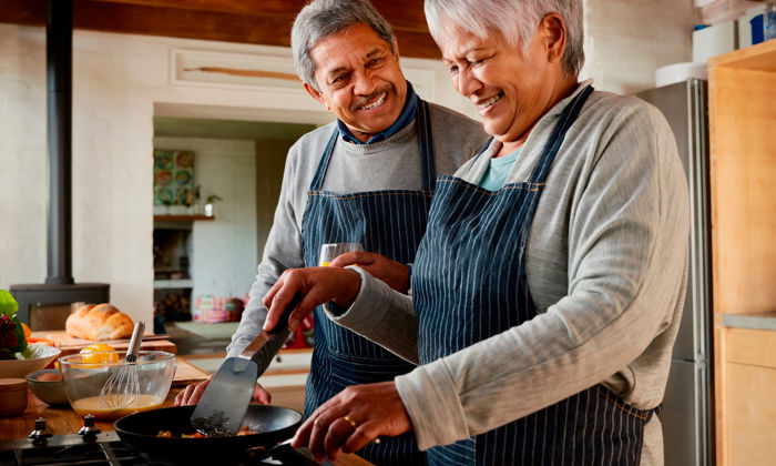 Bienfaits de cuisiner : une femme et un homme, portant des tabliers, préparent un repas avec un mélange d’œufs. 