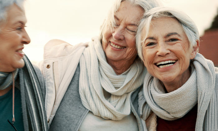 Santé cognitive : trois femmes sont à l’extérieur, souriantes, profitant d’un moment ensemble. 
